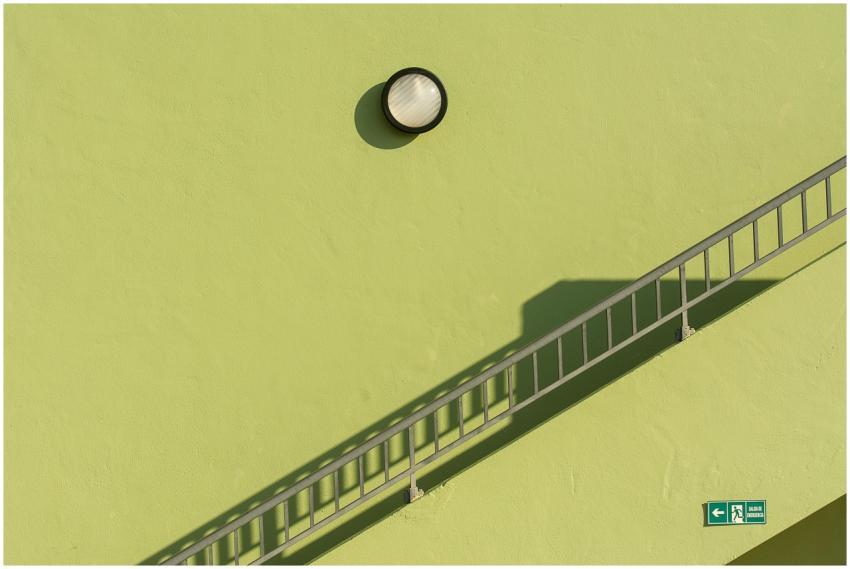 A green wall with a modern lamp and railing create