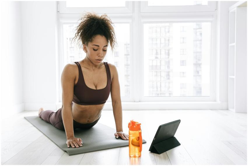 A woman in activewear performs yoga on a mat indoo