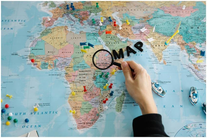 Hand using magnifying glass on a colorful map, wit