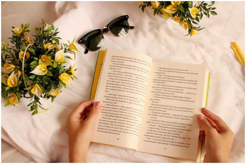 Hands holding a book surrounded by yellow flowers