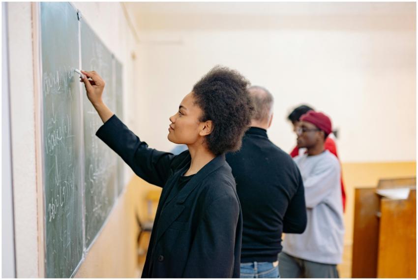 A young student writing on a blackboard in a class