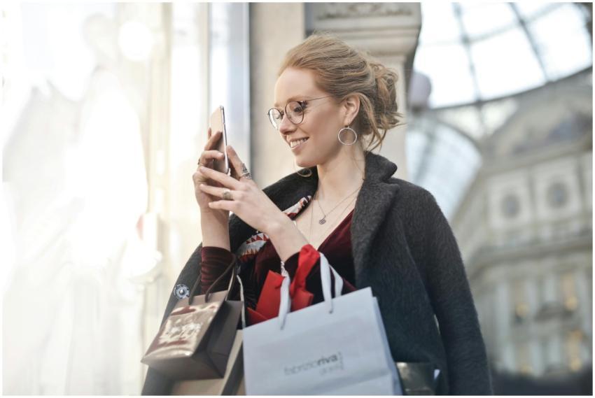 Stylish woman with shopping bags using smartphone