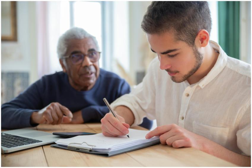 A young man aids a senior citizen with writing at
