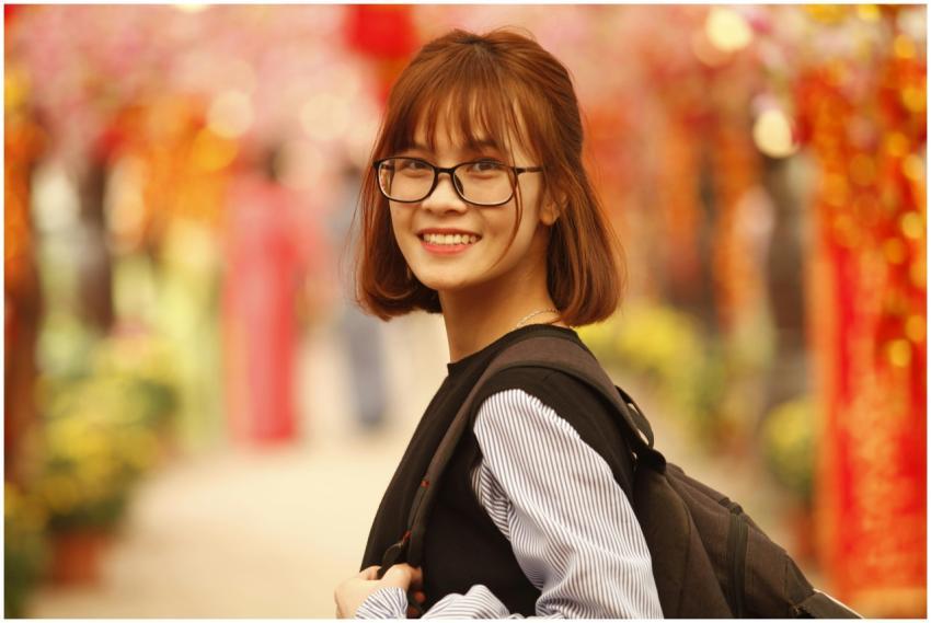 Young woman with glasses and backpack smiling outd