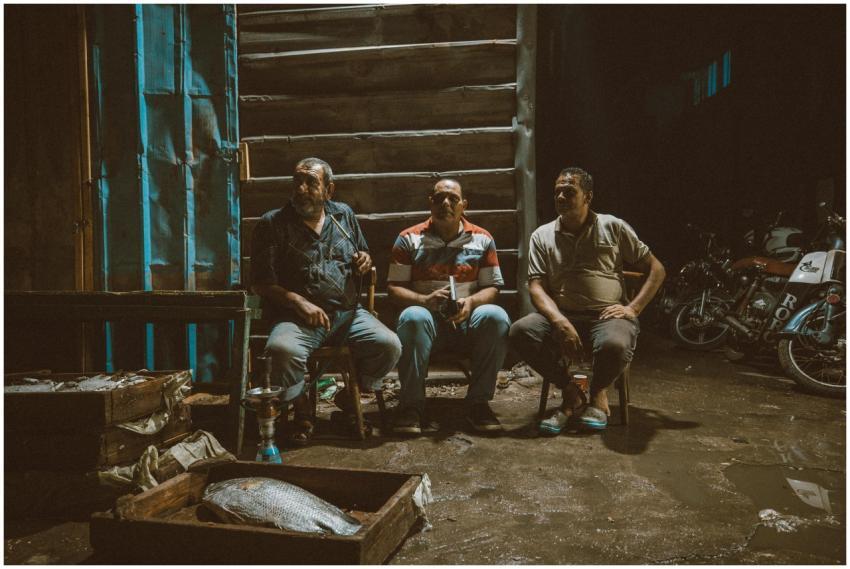 Three men sitting at a fish market in Ras El-Bar,