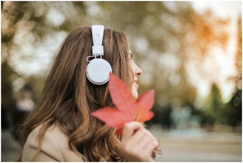 Woman with headphones enjoys music outdoors holdin