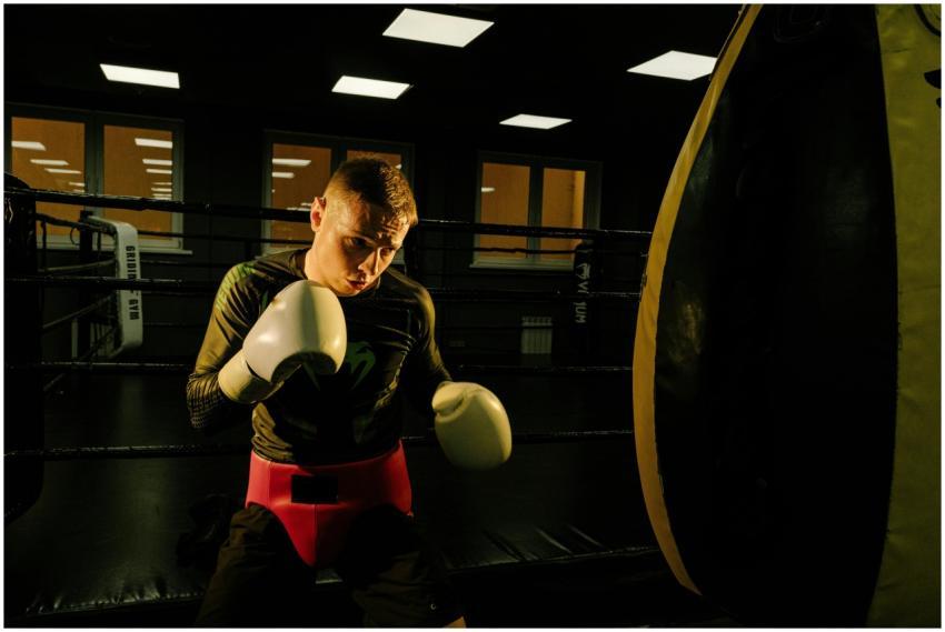 Focused male boxer training with a heavy bag in a