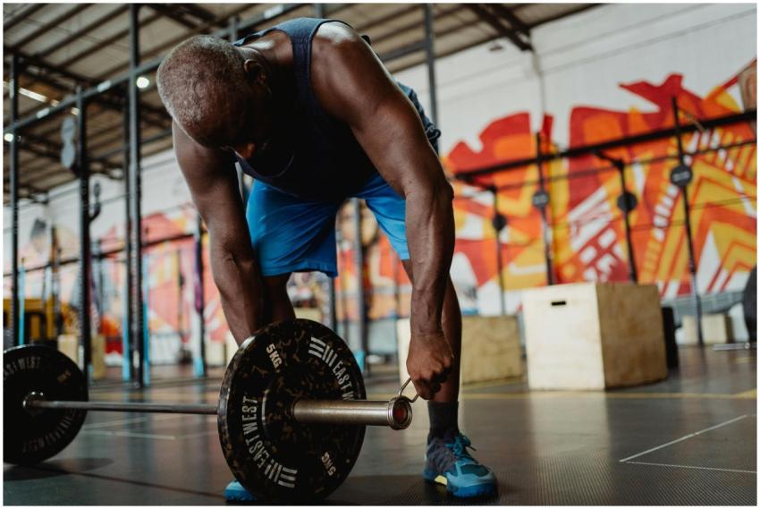An African American man lifting a barbell in a vib