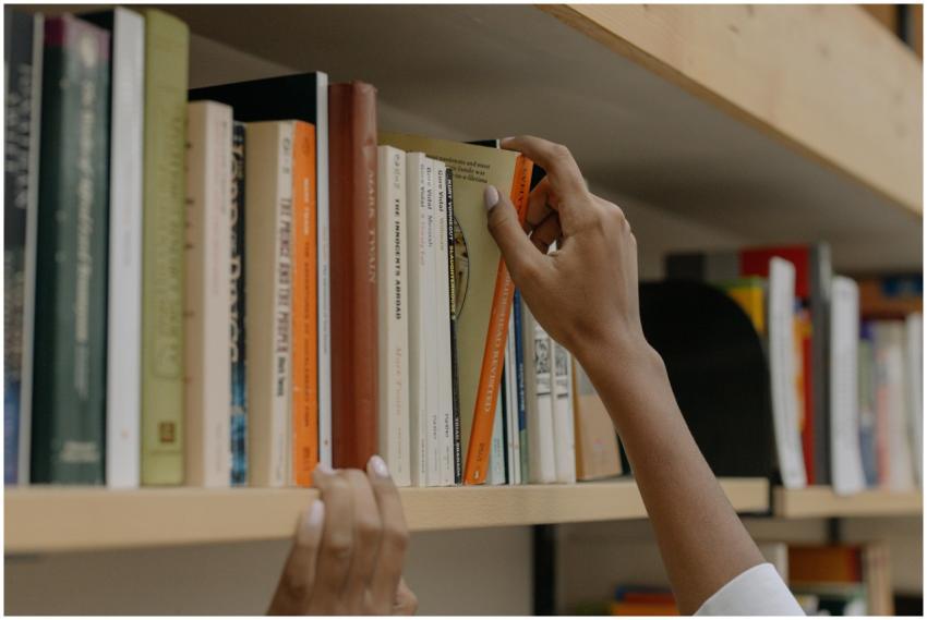 A person choosing a book from a library shelf show