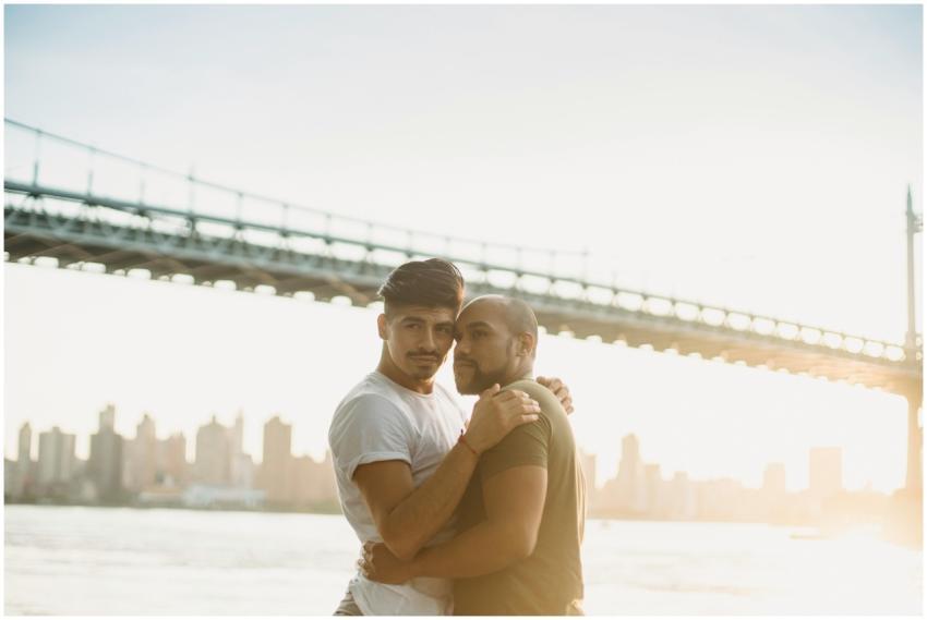 A loving gay couple embraces by the river with a c