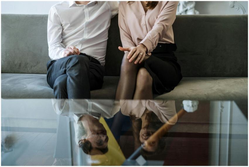 A couple sitting on a sofa, reflecting on glass ta