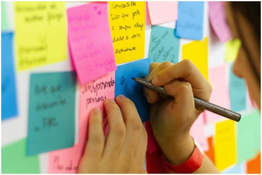Hands writing on colorful sticky notes during a br