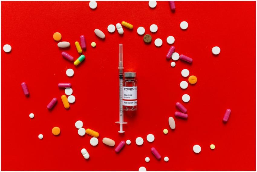 Vaccine vial and syringe surrounded by colorful pi