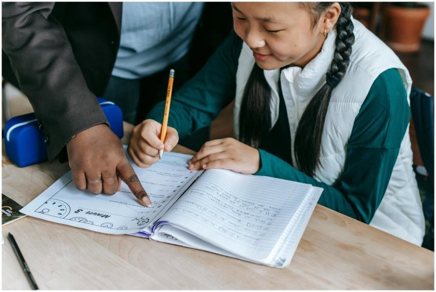 High angle of crop black teacher helping Asian gir