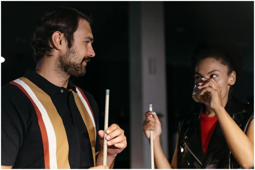 A man and woman socializing over billiards, holdin