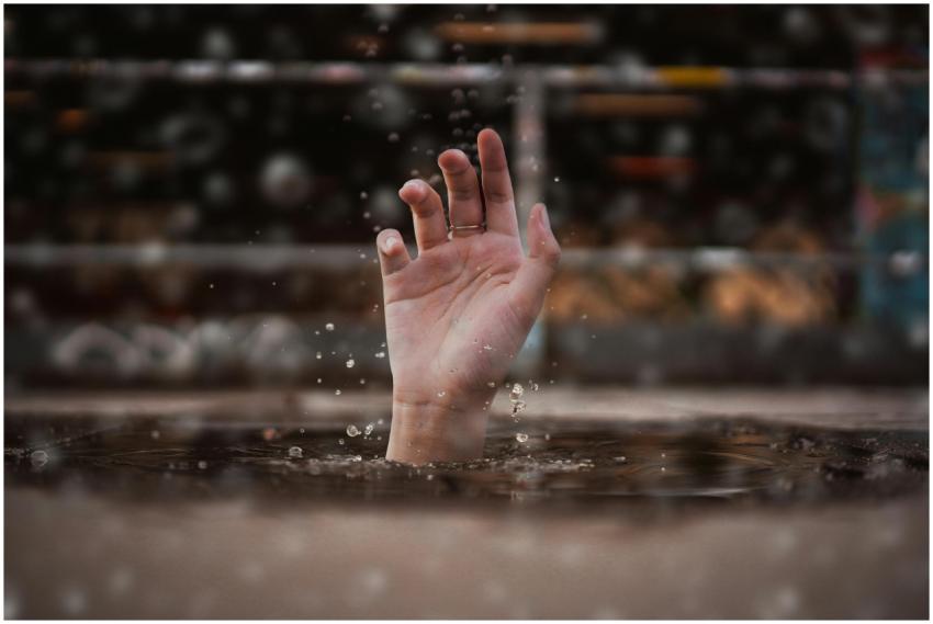 A single hand emerges from water, symbolizing a cr