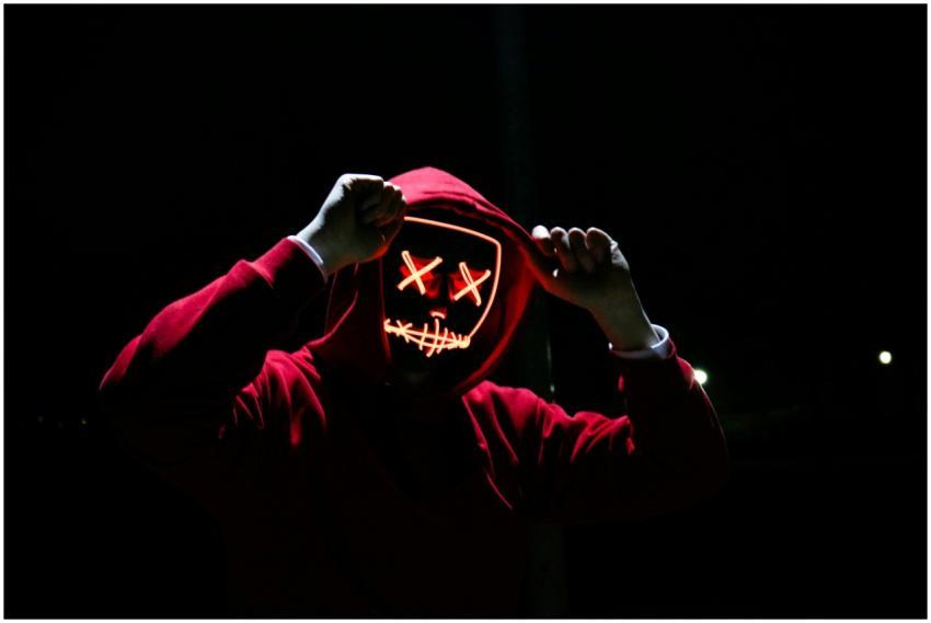 A spooky illuminated mask figure with a red hoodie