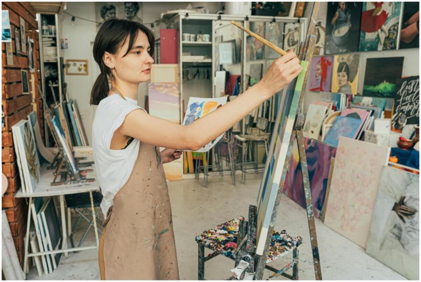 A young female artist painting on a canvas in an a