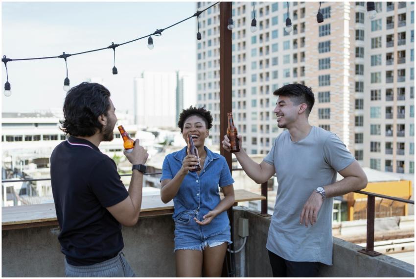 Three friends laughing and enjoying drinks on a ro