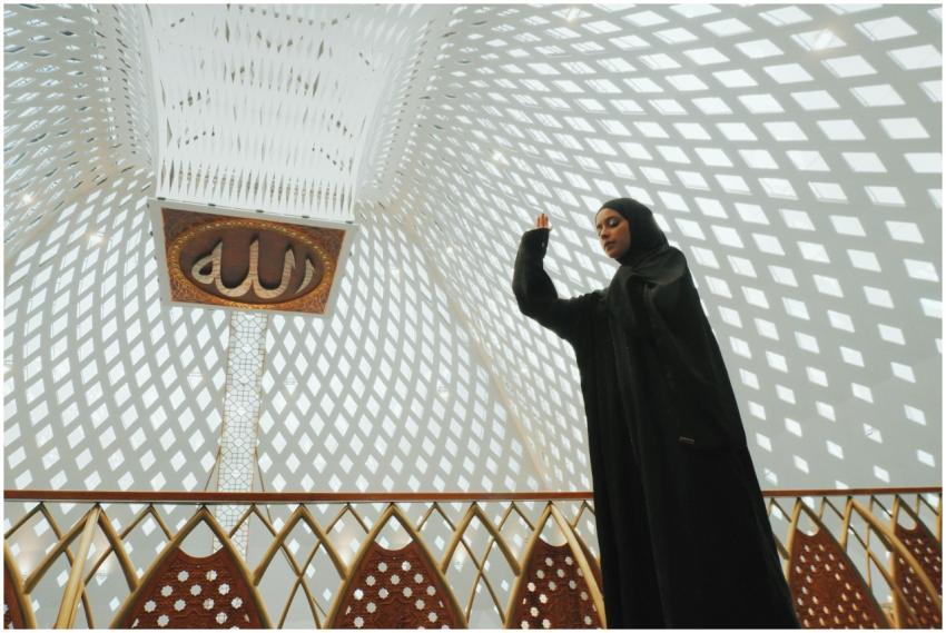 A Muslim woman in traditional attire prays inside