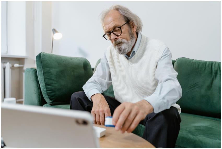 Elderly man with glasses using a tablet for telehe