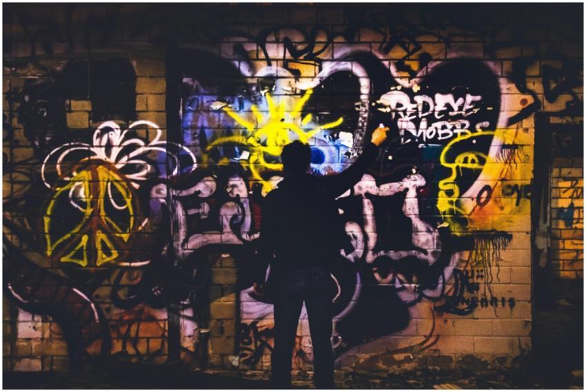 Street artist painting colorful graffiti on a bric