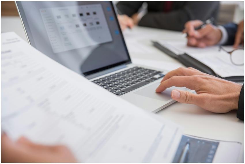Close-up of hands working on documents and a lapto