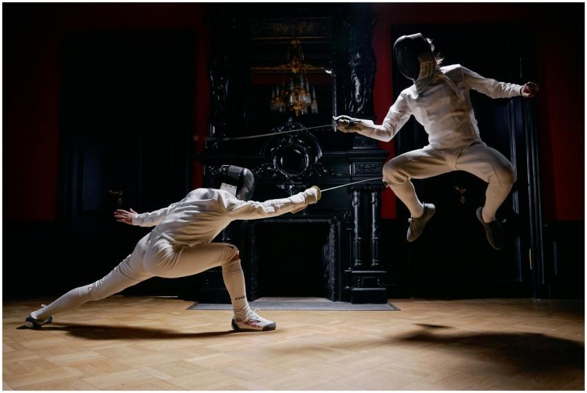 Two fencers engage in a dynamic duel, one leaping,
