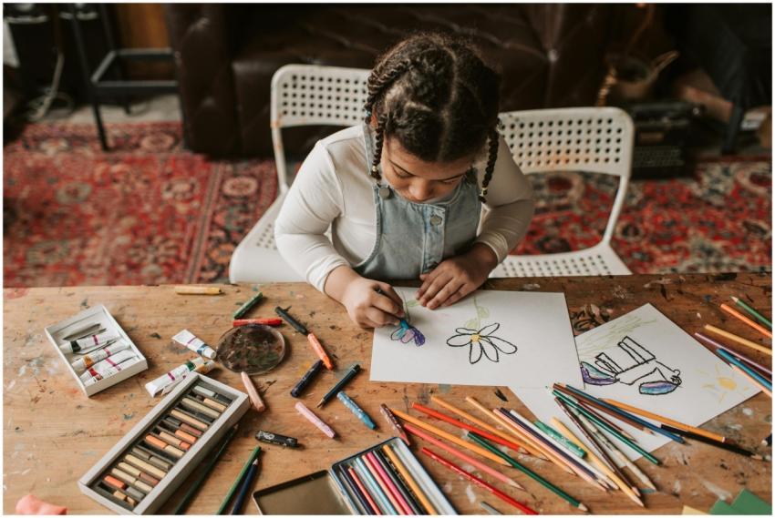 A young girl focused on drawing with crayons and c