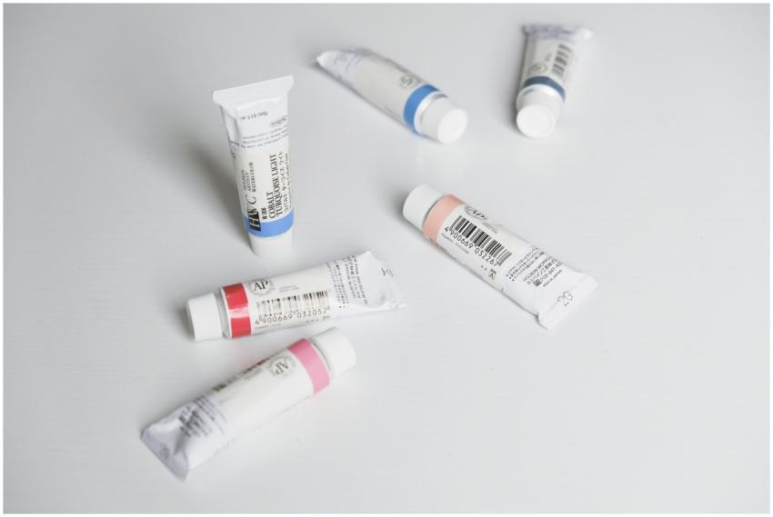 Close-up of colorful paint tubes arranged on a whi