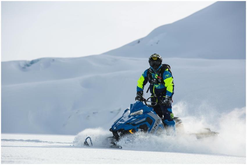 A person riding a snowmobile through a snowy mount