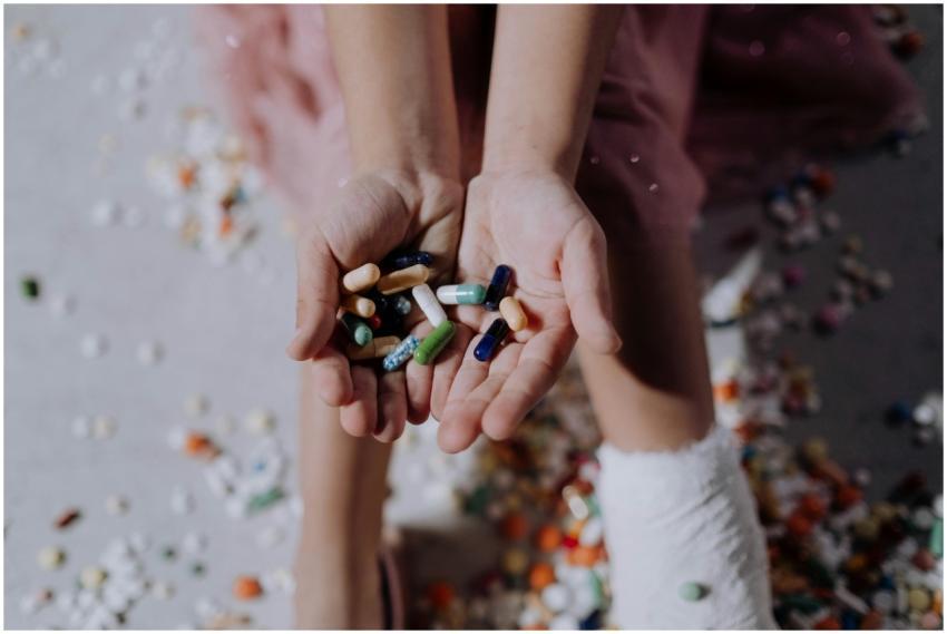 Close-up of a child holding pills with an injured