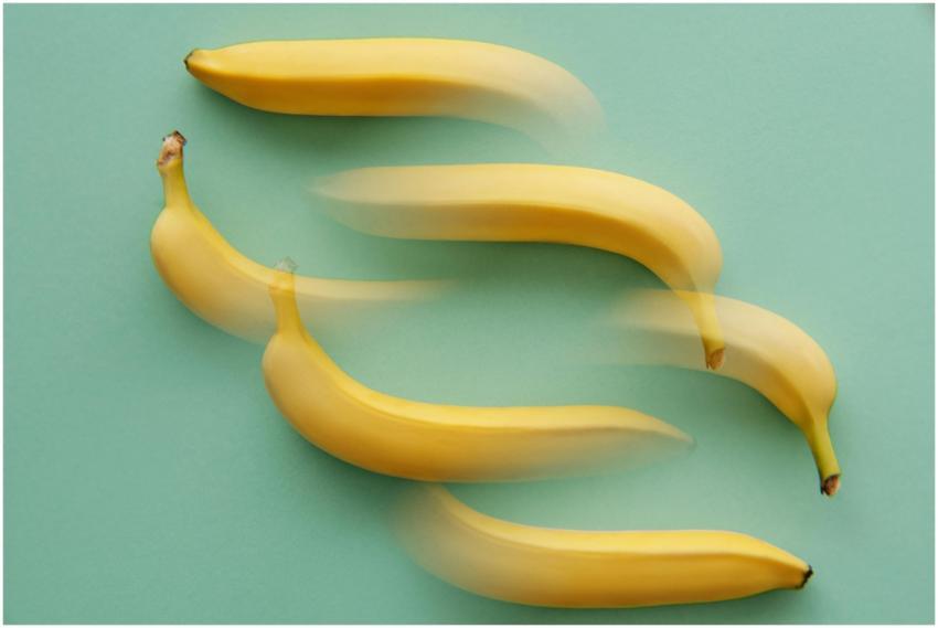 Artful display of moving bananas on a mint green b