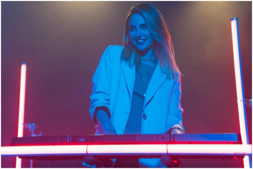 A happy female DJ in a blazer playing keyboards un