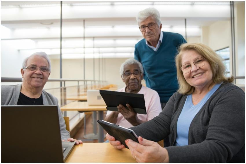 Elderly group using digital tablets and laptops in