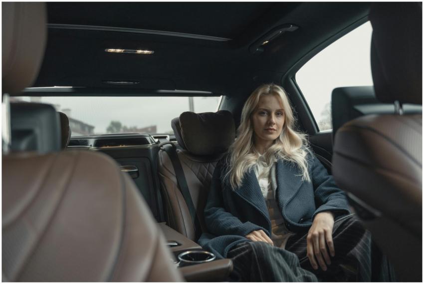 Elegant woman in a blue coat sitting in the back s