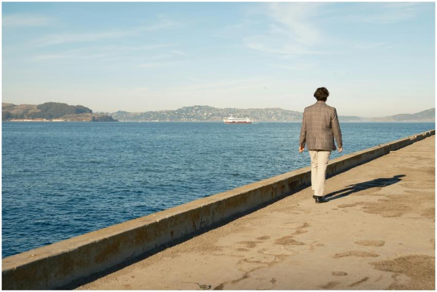 A man walks along a pier overlooking the ocean in
