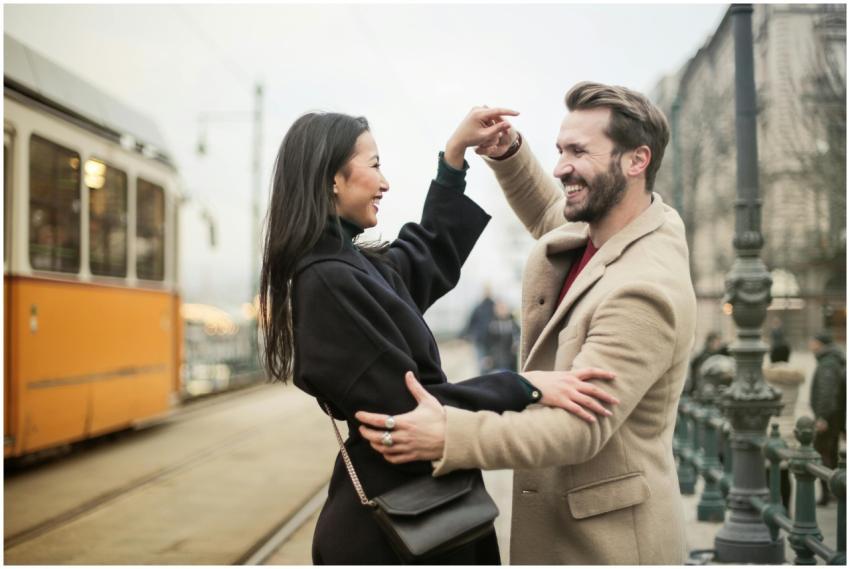 Joyful couple dances on a tram-lined city street,