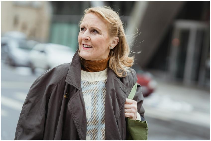 Cheerful senior female in coat with bag and flying