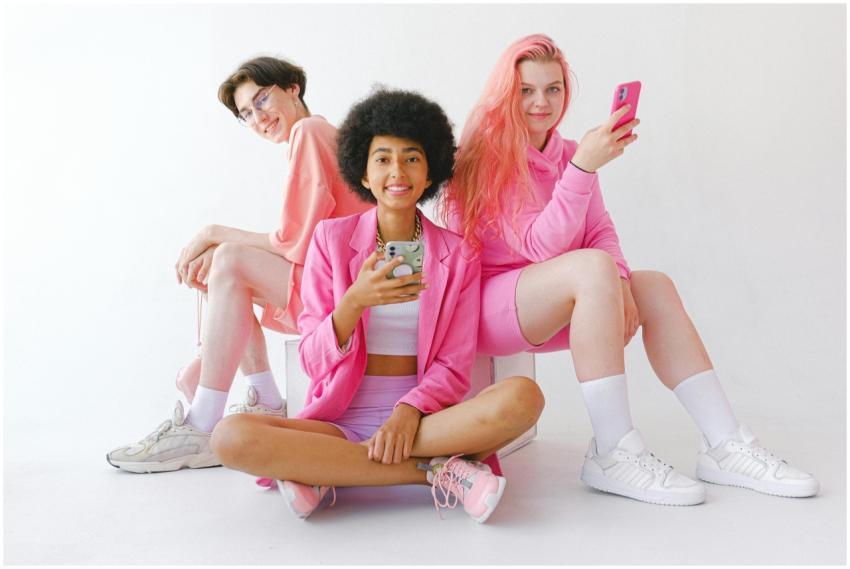 Group of teens in pink outfits using smartphones a