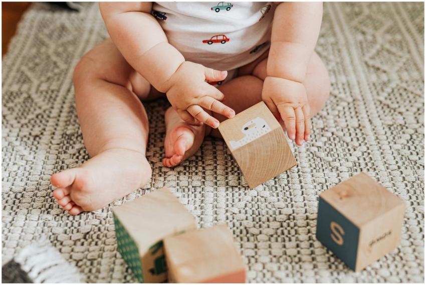A baby sitting and playing with wooden toy blocks
