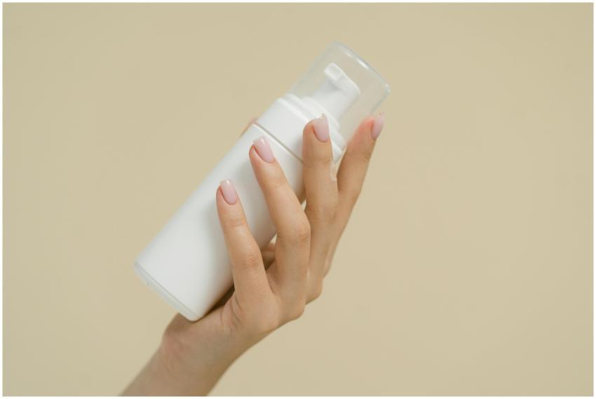 A close-up of a hand holding a white cosmetic bott