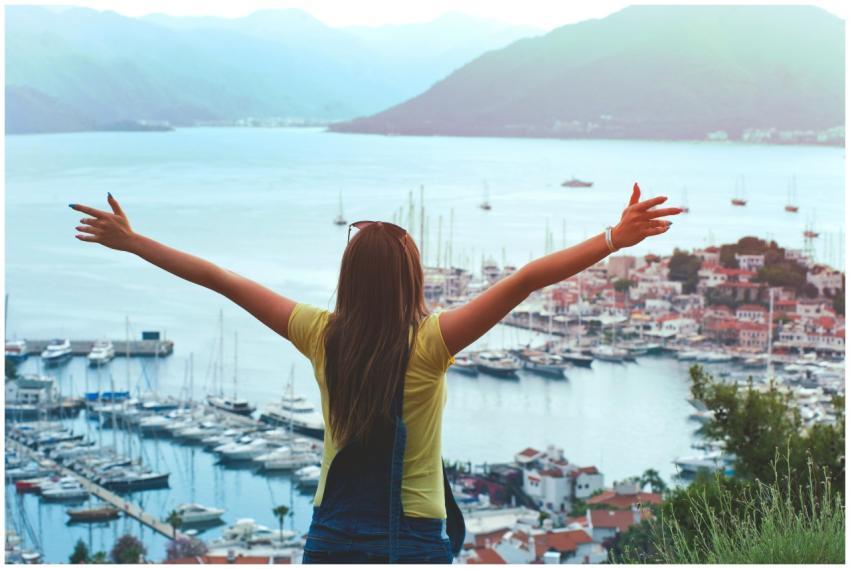 A woman with open arms enjoys a scenic summer view