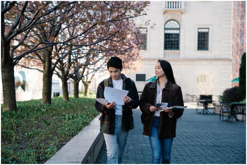 Two teenagers holding papers, walking through a ca
