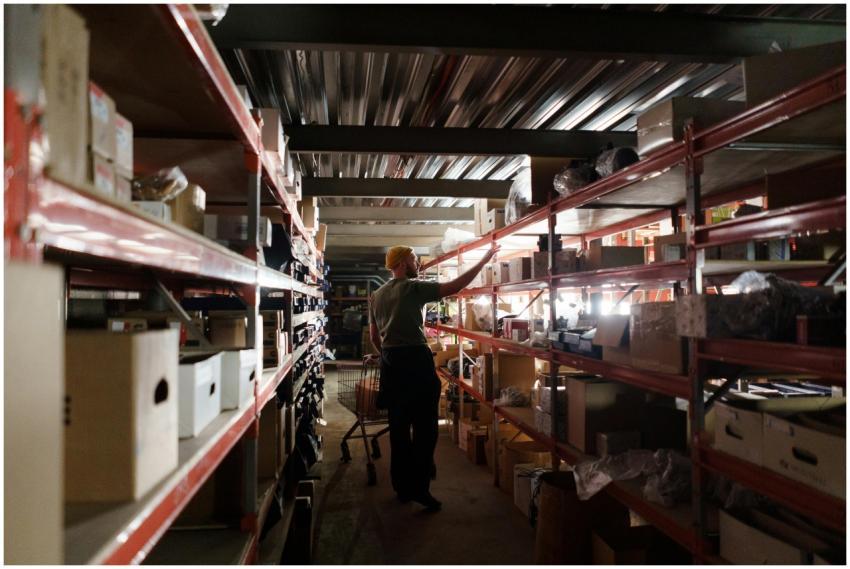 A warehouse worker arranging inventory on metal sh