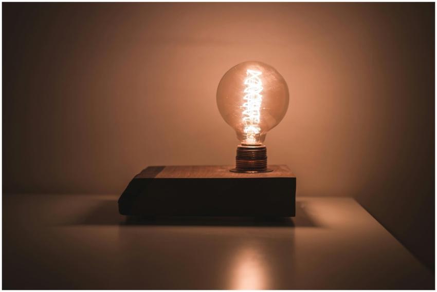 A glowing vintage-style lightbulb on a wooden base