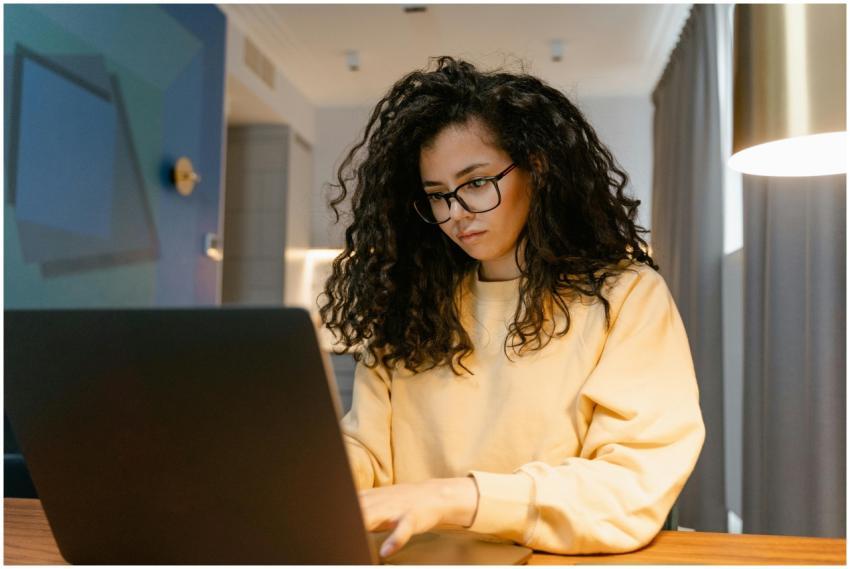 Woman in yellow sweater working on a laptop in a c