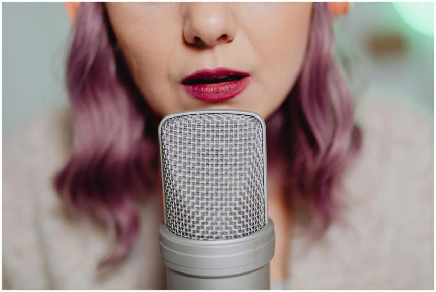 Close-up of a woman with purple hair speaking into