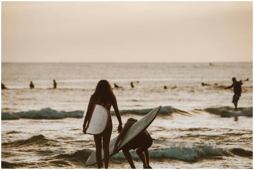 Surfers walk towards waves in Honolulu, Hawaii, at