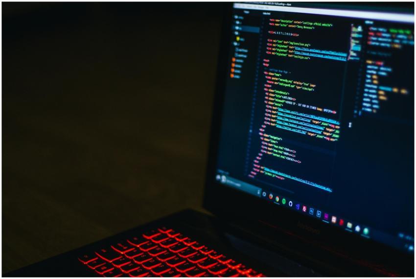 Red backlit keyboard and code on laptop screen cre